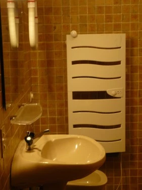 salle de bain équipée d'une sèche serviettes, une baignoire/douche, lavabo et d'un grand miroir